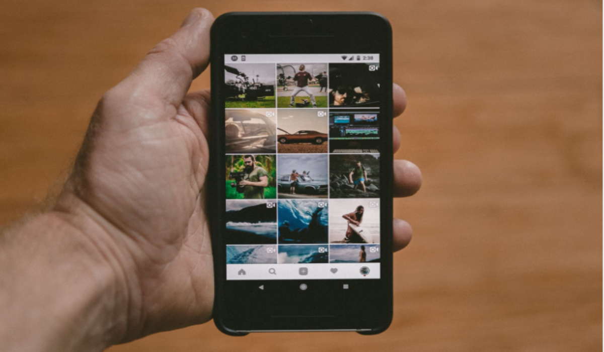 Man holding a smartphone with an Instagram account displayed on the screen